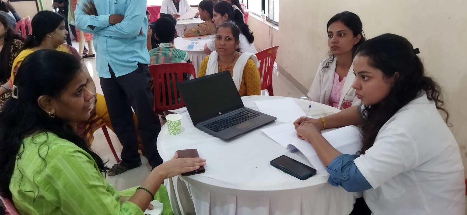 DigiAbility staff helping beneficiaries with applications at a camp table